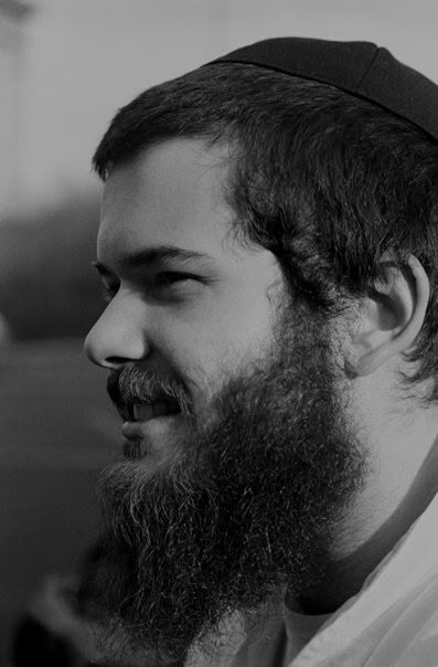 Brandon Sufrin, laughing, in three-quarter profile.